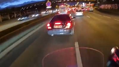 Un motard qui roule à toute vitesse en interfile s'énerve contre un automobiliste qui change de voie