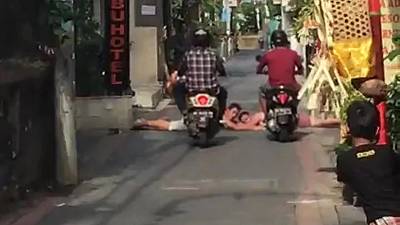 Un scootériste roule sur une personne allongé qui bloque la route